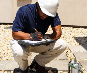 Person with a clipboard looking at a rooftop anchor
