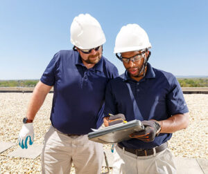 Two people on a rooftop looking at a clipboard.